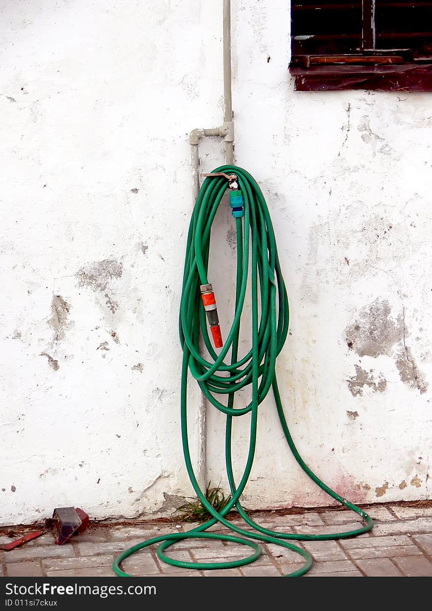 Pipe on the wall and long green hose.