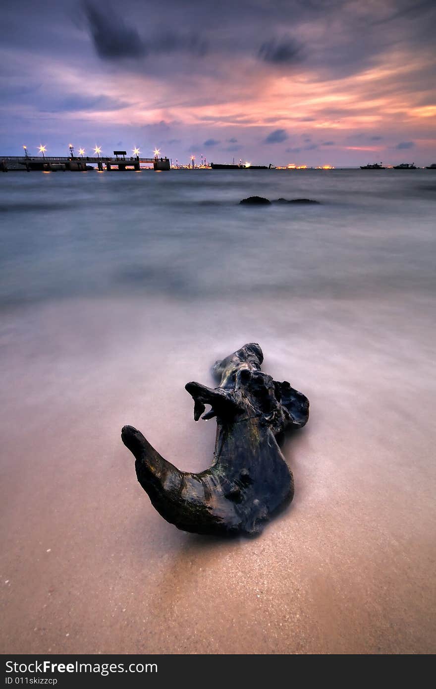 A pink sunset with a lone log on the seashore. A pink sunset with a lone log on the seashore.