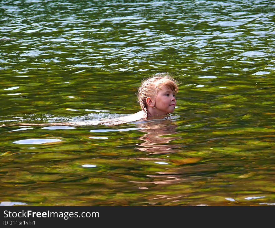 Small girl swims in river with water beautiful green hue. Sunny day, summer. Fussian Far East, Primorye. Small girl swims in river with water beautiful green hue. Sunny day, summer. Fussian Far East, Primorye.