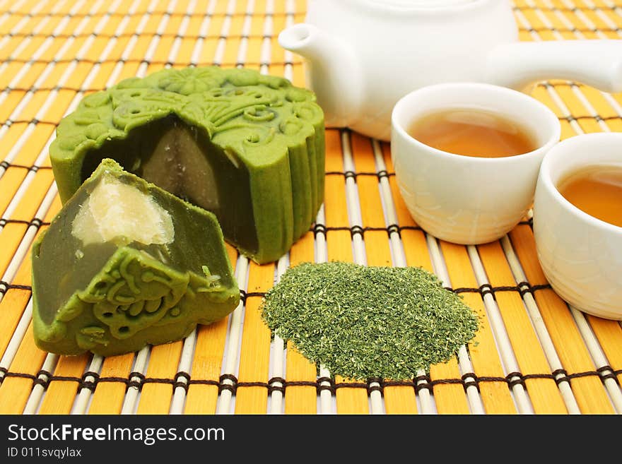 Greentea mooncake slice into quarter put together with teacup and teapot. Greentea mooncake slice into quarter put together with teacup and teapot.