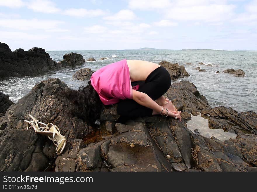 Beautiful woman meditating on the rocks in ireland with her eyes closed,  showing a healthy way to live a happy and relaxed lifestyle in a world full of stress. Beautiful woman meditating on the rocks in ireland with her eyes closed,  showing a healthy way to live a happy and relaxed lifestyle in a world full of stress