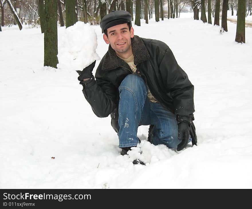 The young man is playing snowballs in the park. The young man is playing snowballs in the park