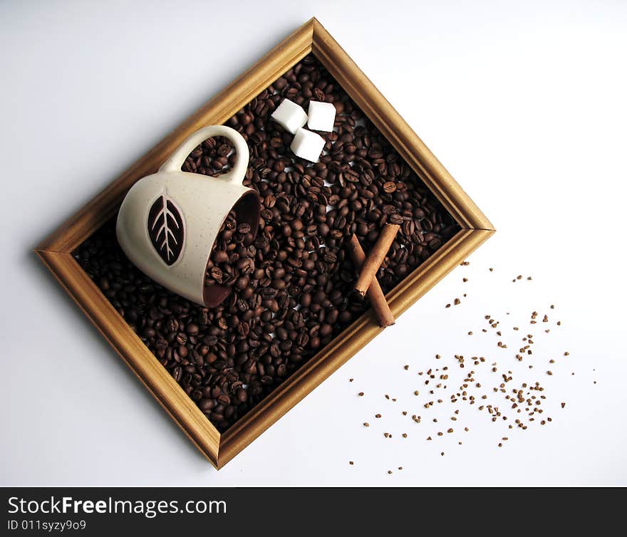 The picture consisting of coffee grains, cinnamon and sugar in a wooden framework. The picture consisting of coffee grains, cinnamon and sugar in a wooden framework