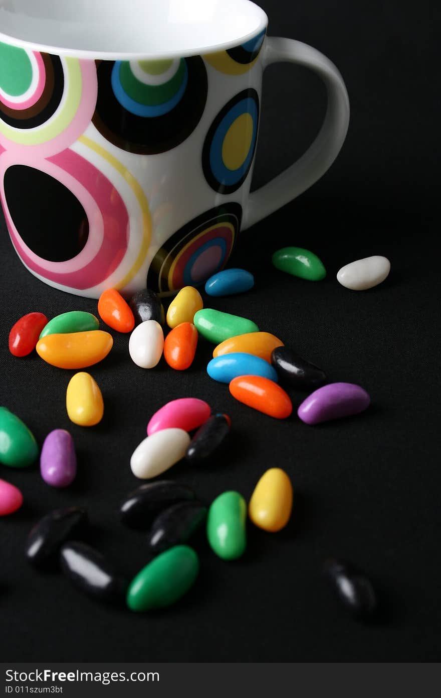 Jelly beans and a mug on a black background. Jelly beans and a mug on a black background