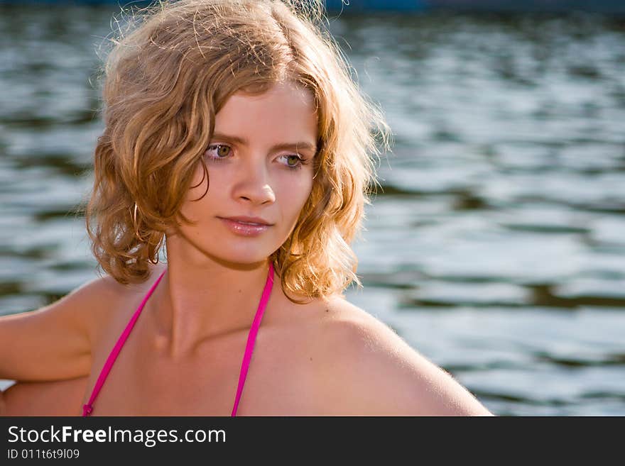 Beautiful girl in beams of the coming sun on a background of water with waves. Beautiful girl in beams of the coming sun on a background of water with waves