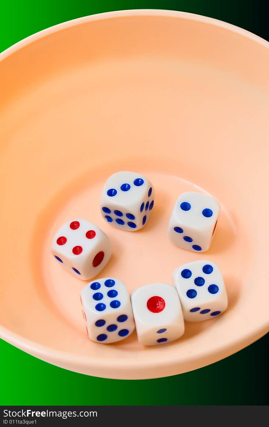 Dices in orange glass on dark green background