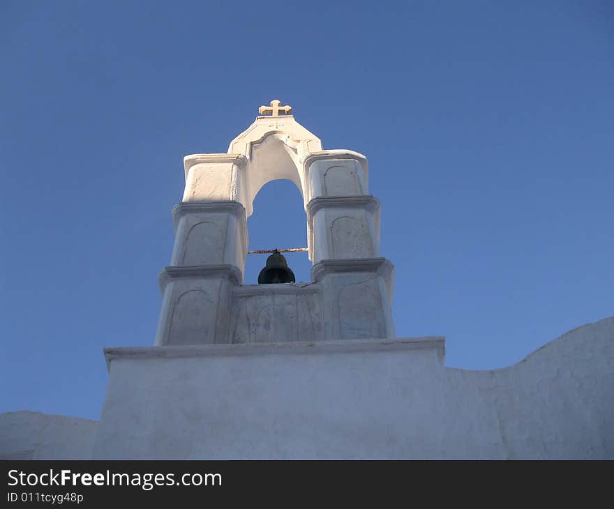 Sunshine on the cross of a bell tower of Greek Chapel - catching the day's last rays of sun on Mykonos Island, Greece, Europe. Sunshine on the cross of a bell tower of Greek Chapel - catching the day's last rays of sun on Mykonos Island, Greece, Europe