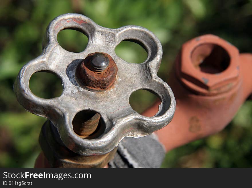 An old rusty tap on a green background. An old rusty tap on a green background