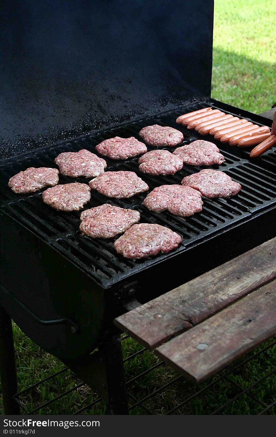 Some hambugers and hotdogs are put on the grill for a cookout. Some hambugers and hotdogs are put on the grill for a cookout.