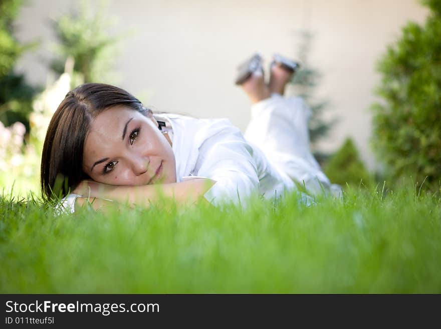 Happy brunette woman lying on grass. Happy brunette woman lying on grass