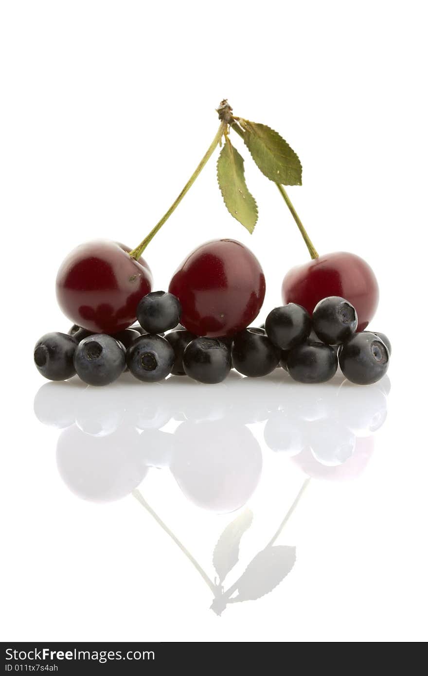 Ripe cherries and bilberries reflected on white background. Ripe cherries and bilberries reflected on white background