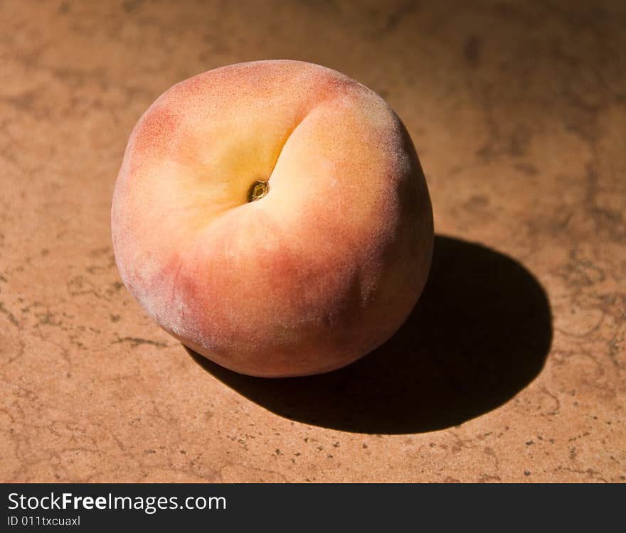 A single peach in the sun.