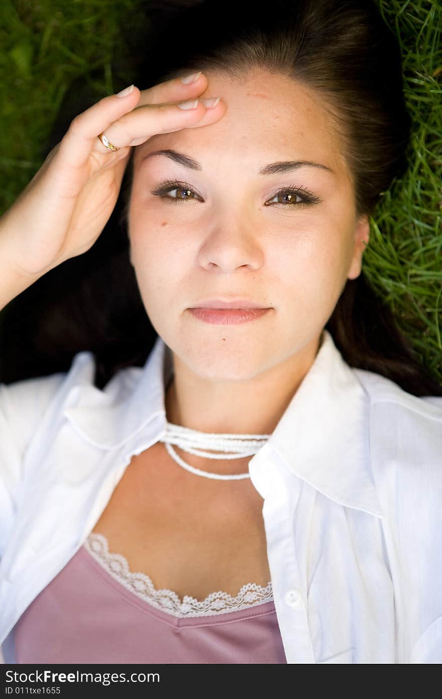 Happy brunette woman lying on grass. Happy brunette woman lying on grass