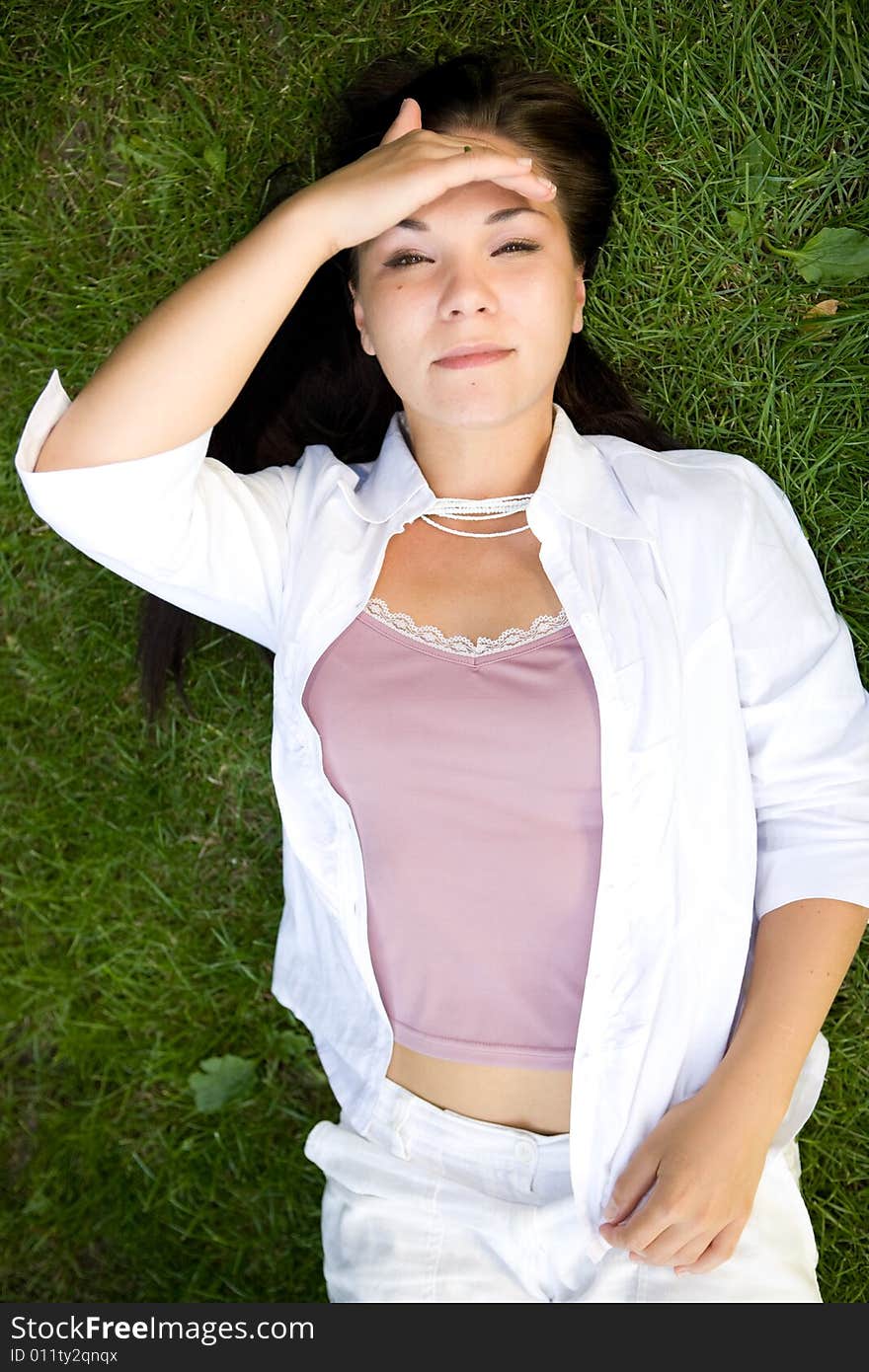 Happy brunette woman lying on grass. Happy brunette woman lying on grass