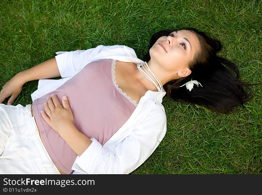 Happy brunette woman lying on grass. Happy brunette woman lying on grass