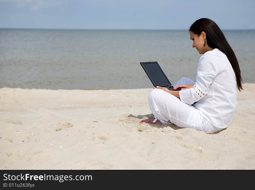 Attractive brunette woman with laptop on the beach