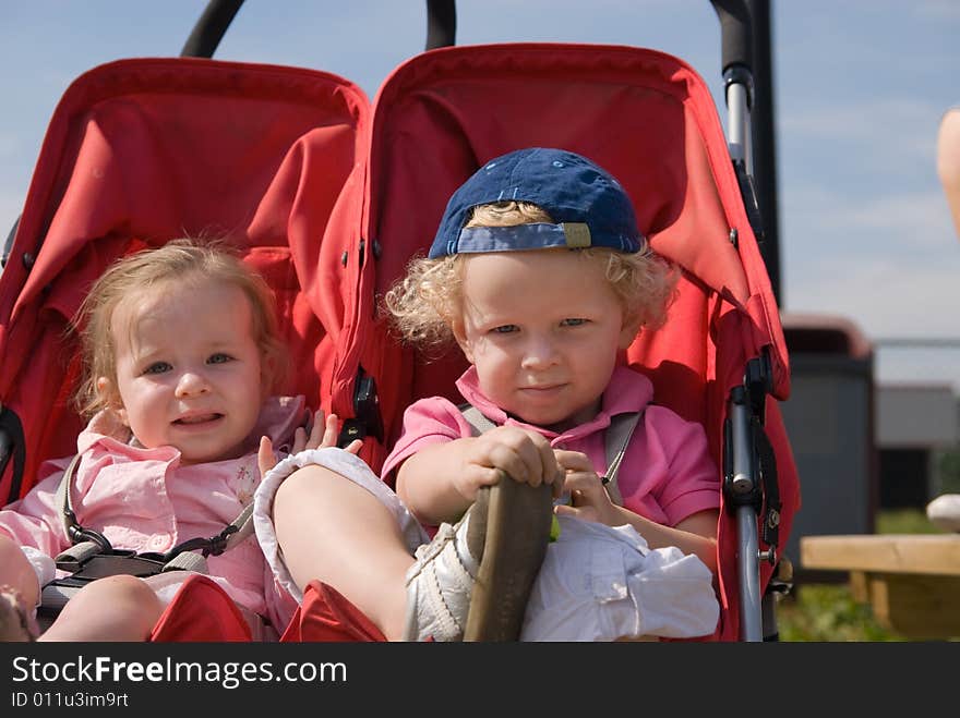 Cute boy and girl in a child carrier