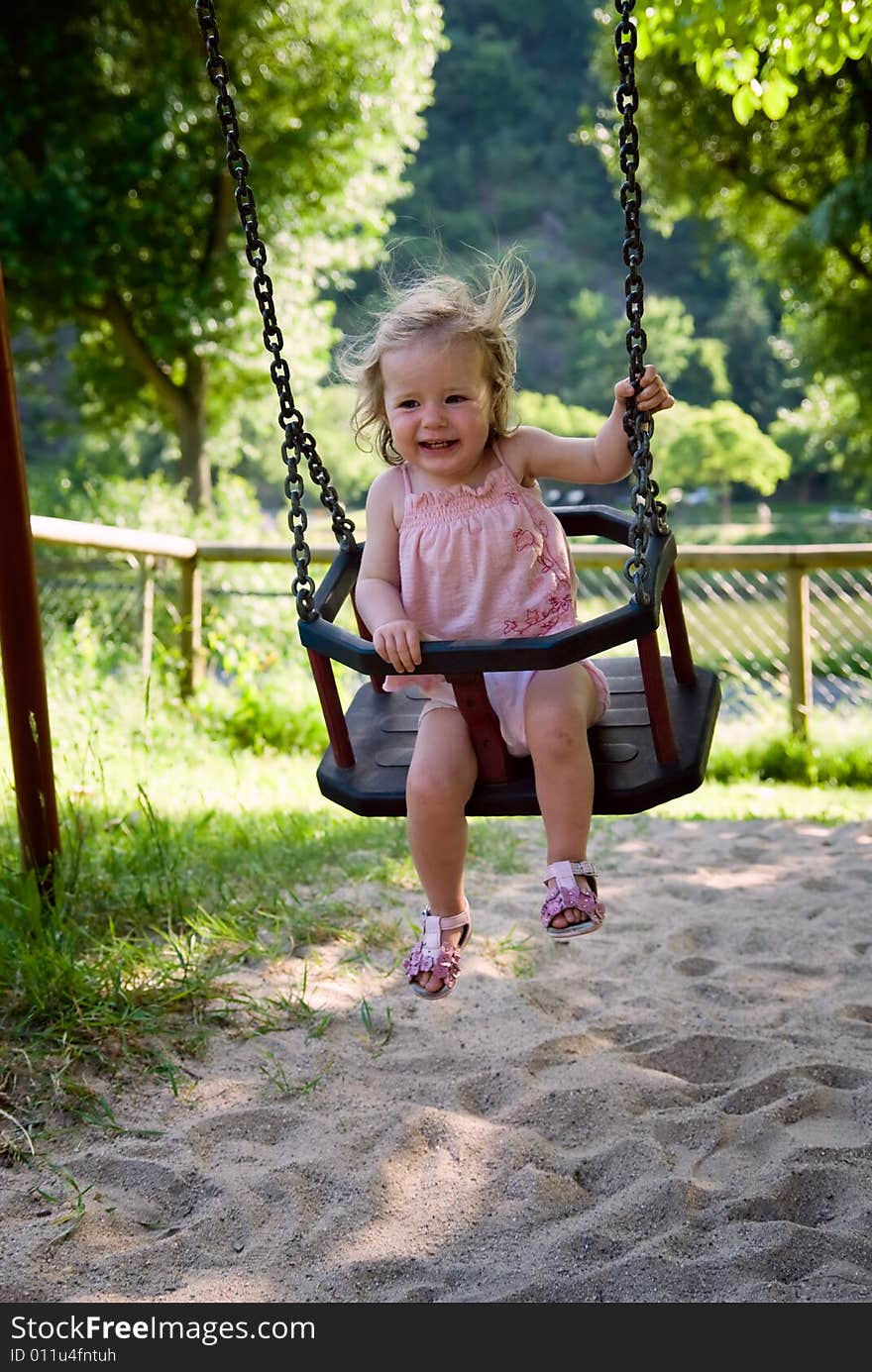 Cute one year old girl having fun on a swing