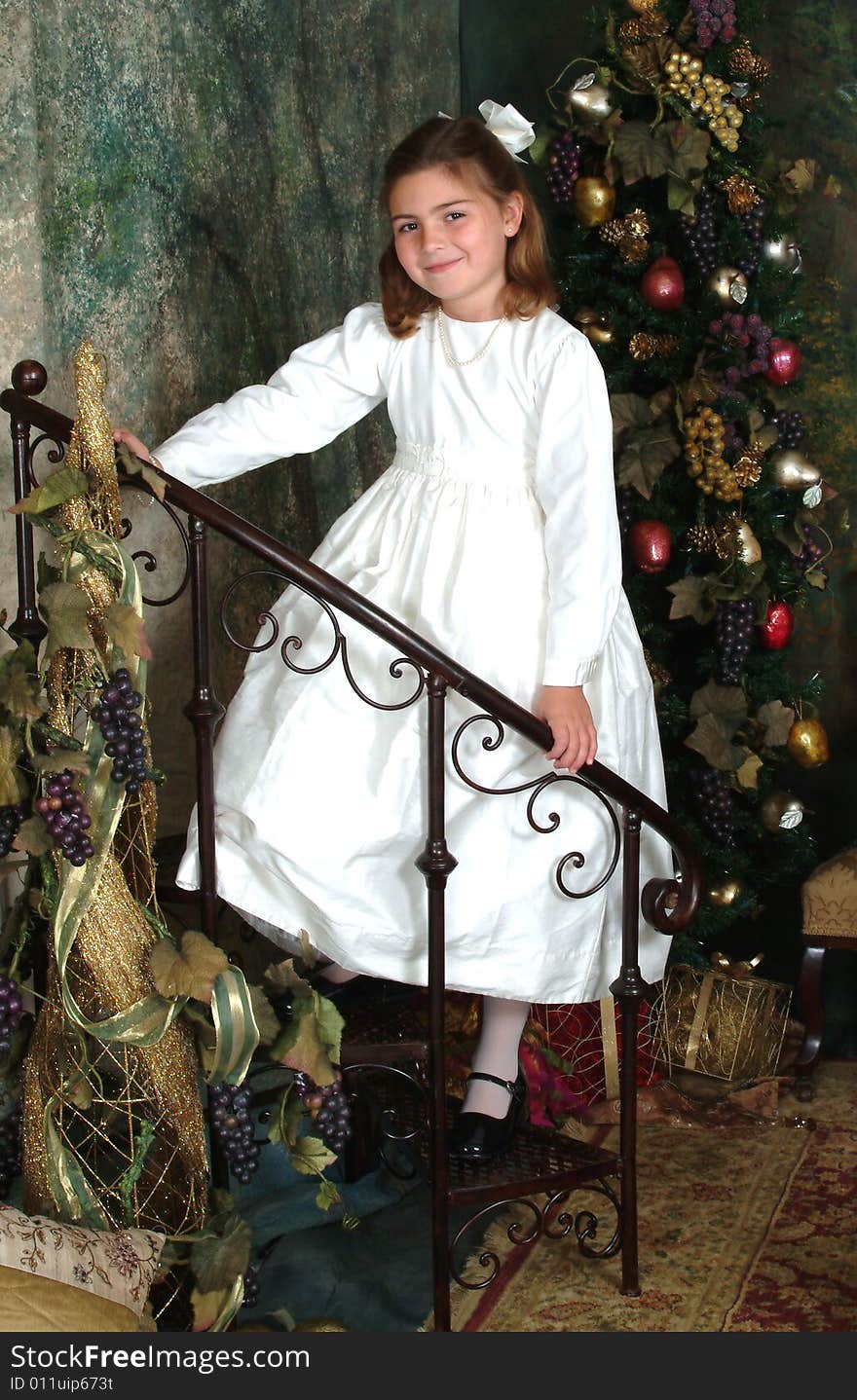 School aged girl on stairs in front of Christmas tree