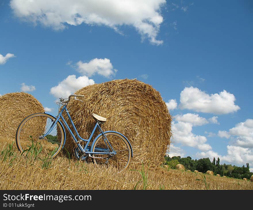 Classic bike, hay bales with blue sky and white clouds. Classic bike, hay bales with blue sky and white clouds