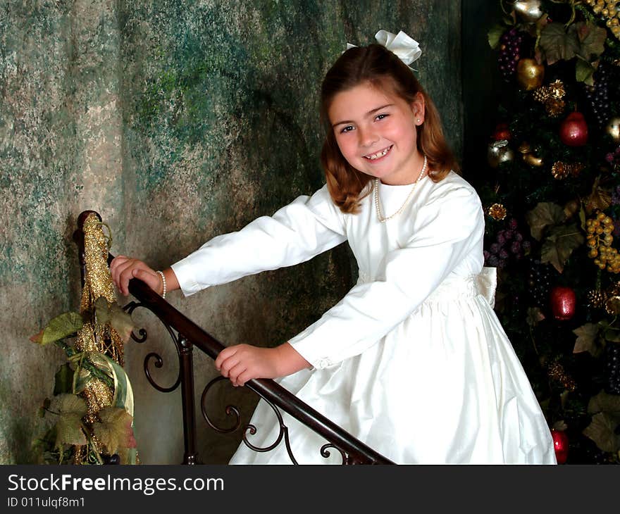 School aged girl holding metal rail in front of Christmas tree. School aged girl holding metal rail in front of Christmas tree