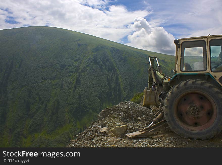 Part of a dredge on a background of a mountain landscape. The beautiful sky. Mountain on a background, cut up by rivulets and clefts. Part of a dredge on a background of a mountain landscape. The beautiful sky. Mountain on a background, cut up by rivulets and clefts