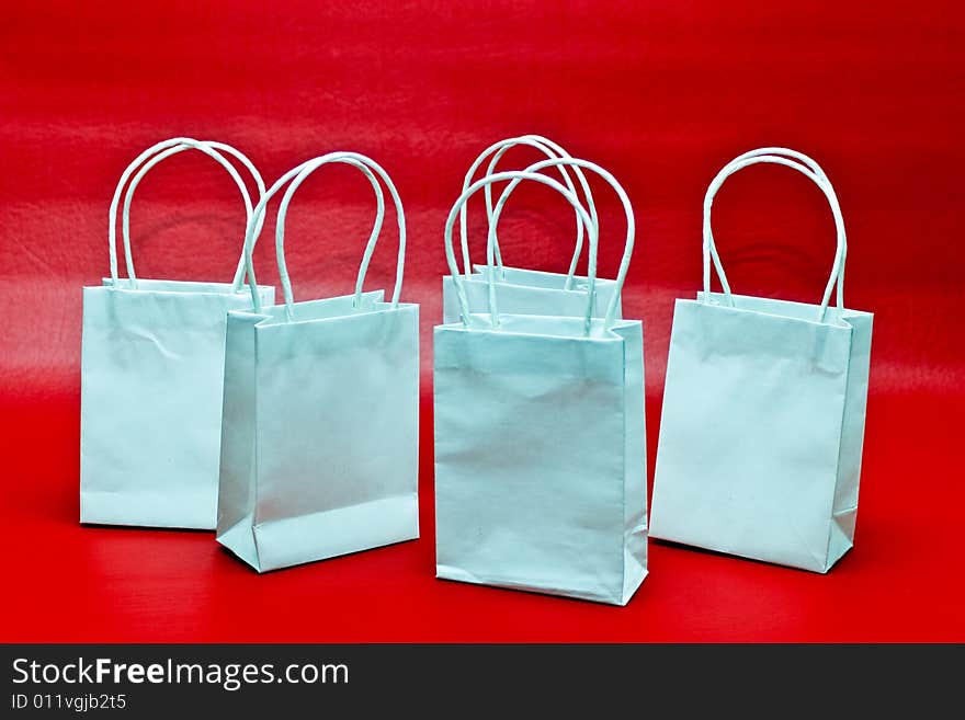 Five white gift bags against a red background. Five white gift bags against a red background.