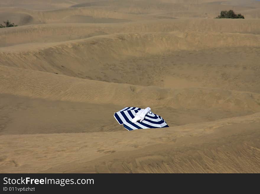 White and blue parasol in front of a sand dune. White and blue parasol in front of a sand dune