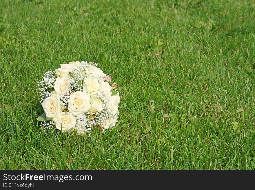 Wedding bouquet from white roses on a green grass