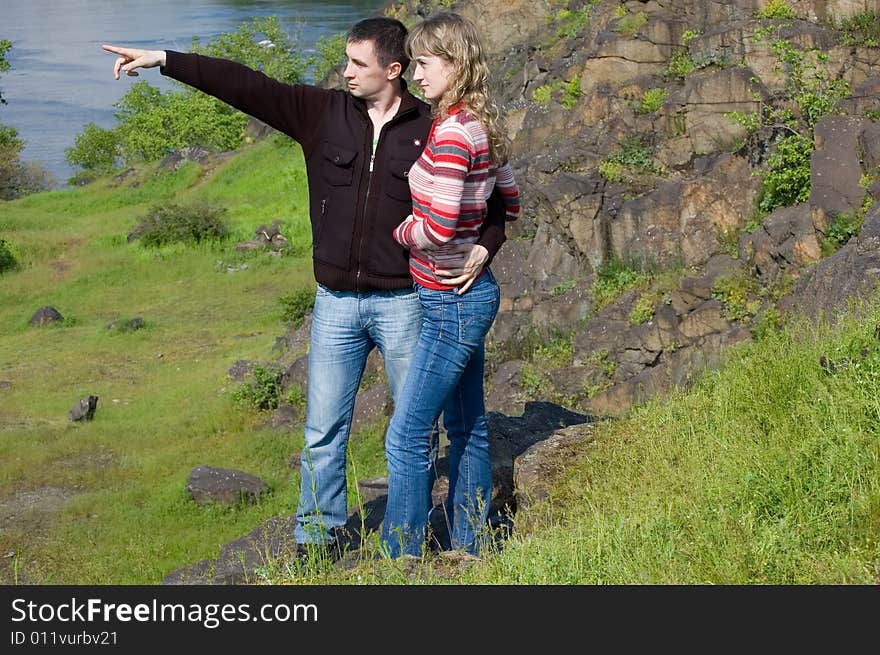 The guy embraces the girl against rocks and specifies in something. The guy embraces the girl against rocks and specifies in something