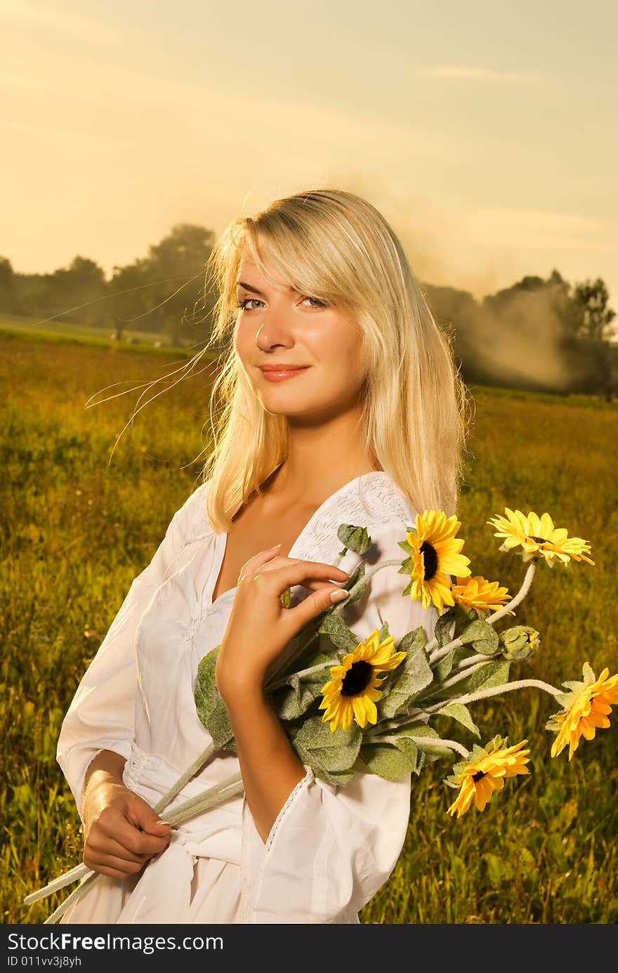 Young beautiful woman with a bouquet of sunflowers in thr field at sunset. Young beautiful woman with a bouquet of sunflowers in thr field at sunset