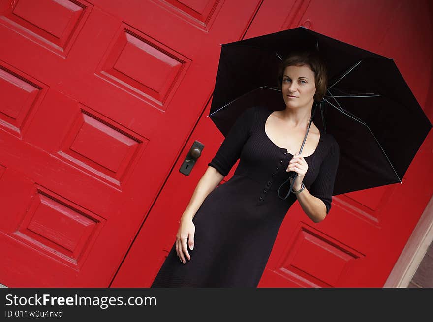 Woman with umbrella in front of red doors.