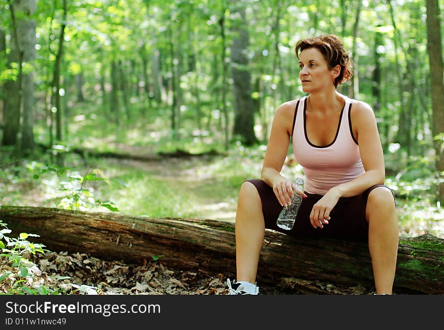 Mature woman runner resting in woods.