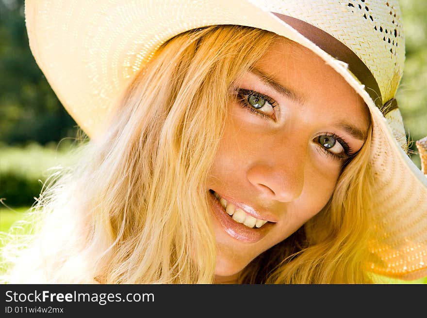 Young blond woman in a hat smiling in a park. Young blond woman in a hat smiling in a park