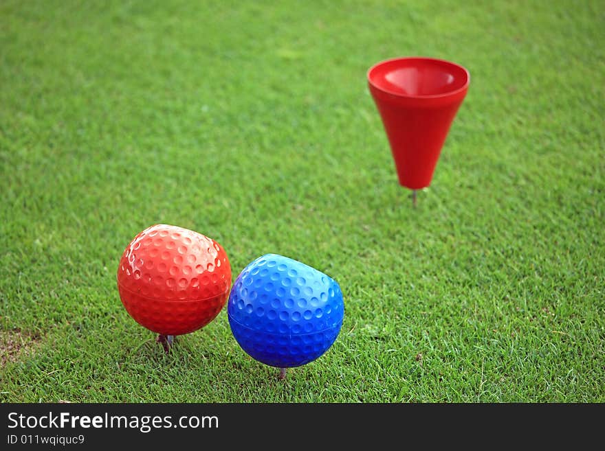 Close view of a red and a blue ball on a tee with a red tee cup. Close view of a red and a blue ball on a tee with a red tee cup