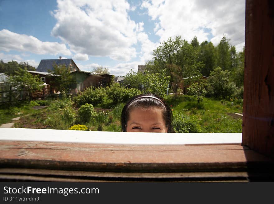 Young smiling woman looking through the window. Young smiling woman looking through the window