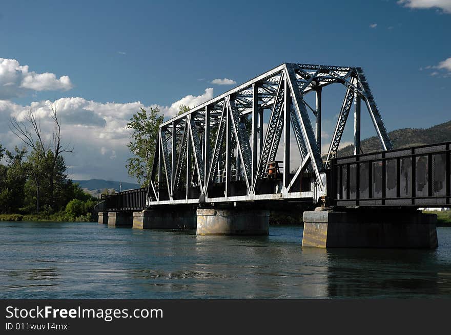 Train tracks over a train bridge over a river.