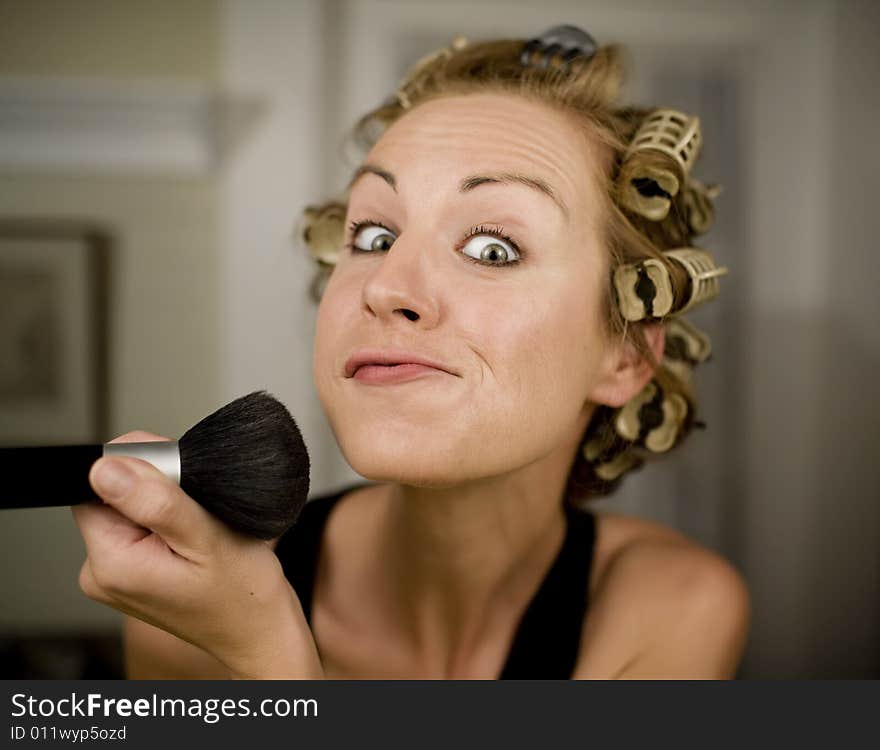 Woman in Curlers Applying Makeup with a Brush. Woman in Curlers Applying Makeup with a Brush