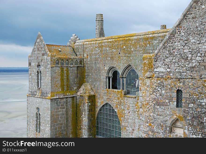 Old stone walls grown with yellow moss, the pastel shades of sky and sand bottom in the background, Saint Michael Abbey at the time of reflux. Old stone walls grown with yellow moss, the pastel shades of sky and sand bottom in the background, Saint Michael Abbey at the time of reflux