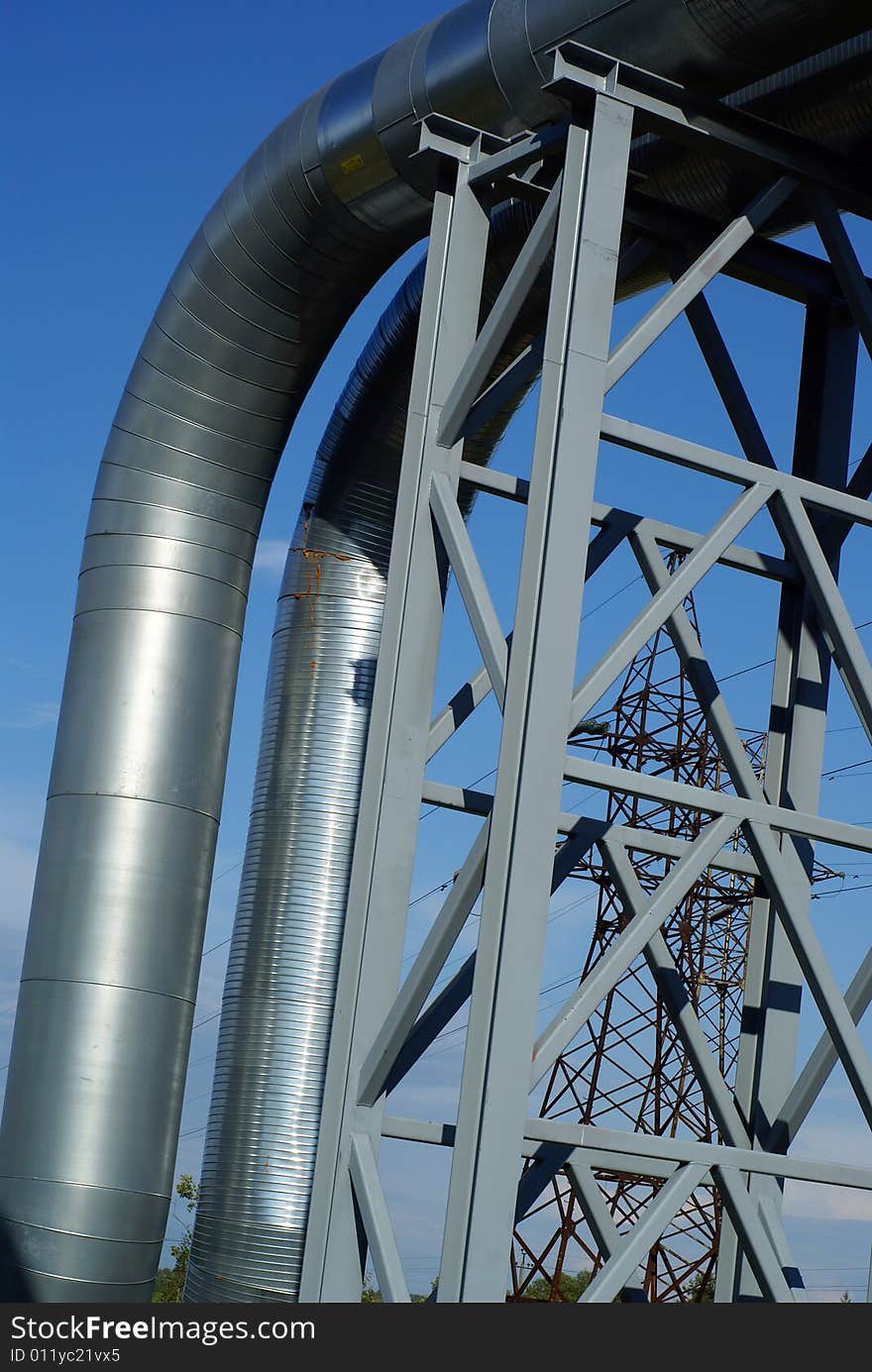 Industrial pipelines on pipe-bridge and electric power lines  against blue sky. Industrial pipelines on pipe-bridge and electric power lines  against blue sky