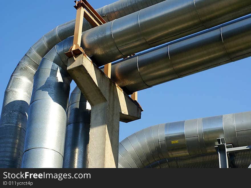 Industrial pipelines on pipe-bridge and electric power lines  against blue sky. Industrial pipelines on pipe-bridge and electric power lines  against blue sky