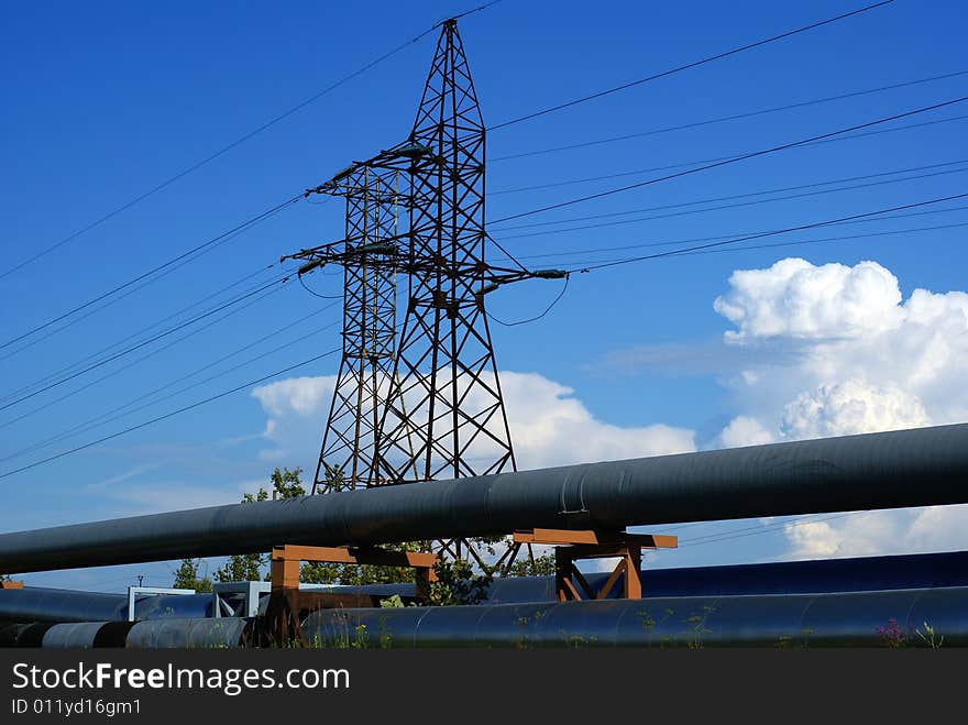 Industrial pipelines on pipe-bridge and electric power lines  against blue sky. Industrial pipelines on pipe-bridge and electric power lines  against blue sky