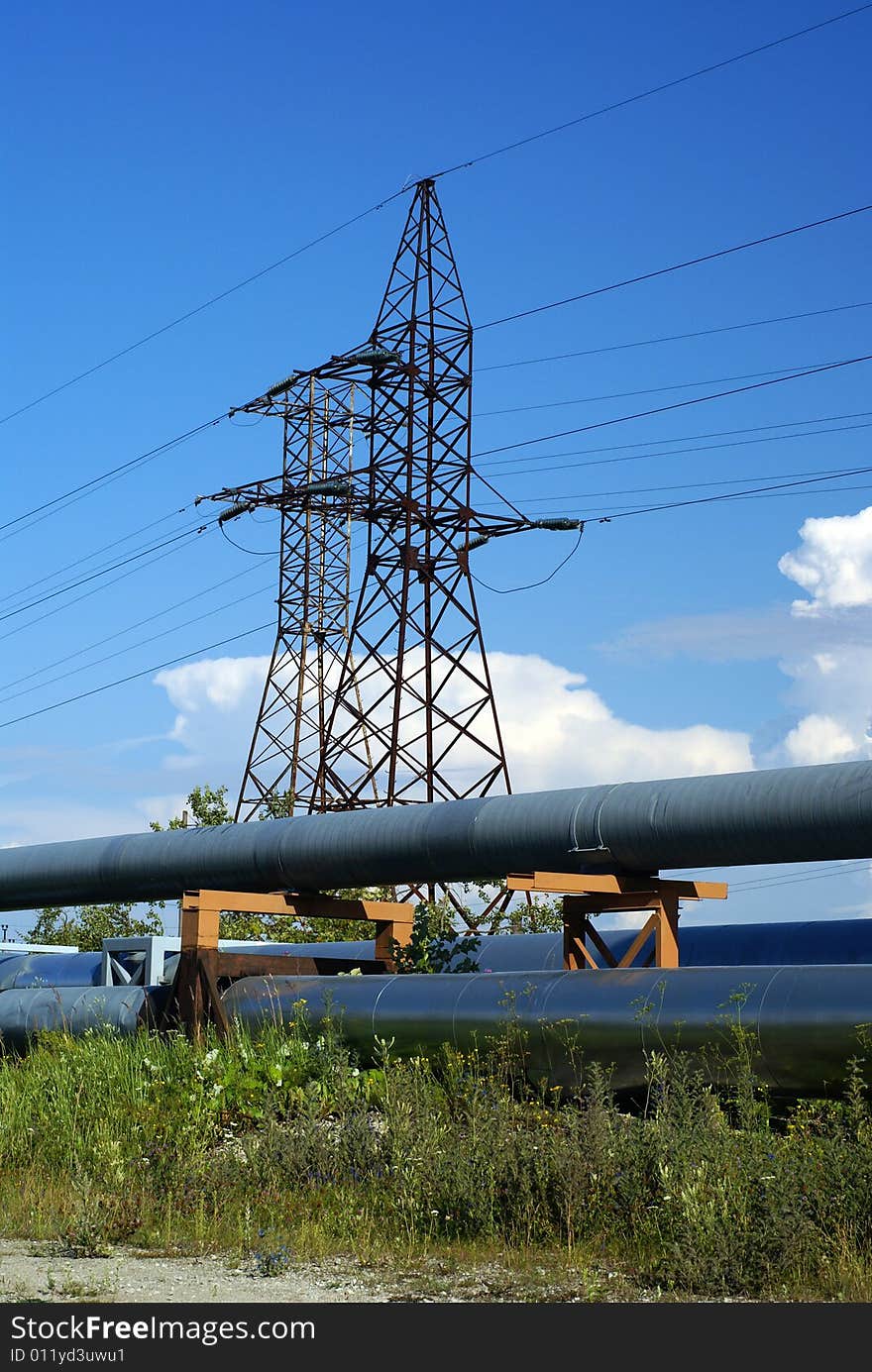 Industrial pipelines on pipe-bridge and electric power lines  against blue sky. Industrial pipelines on pipe-bridge and electric power lines  against blue sky