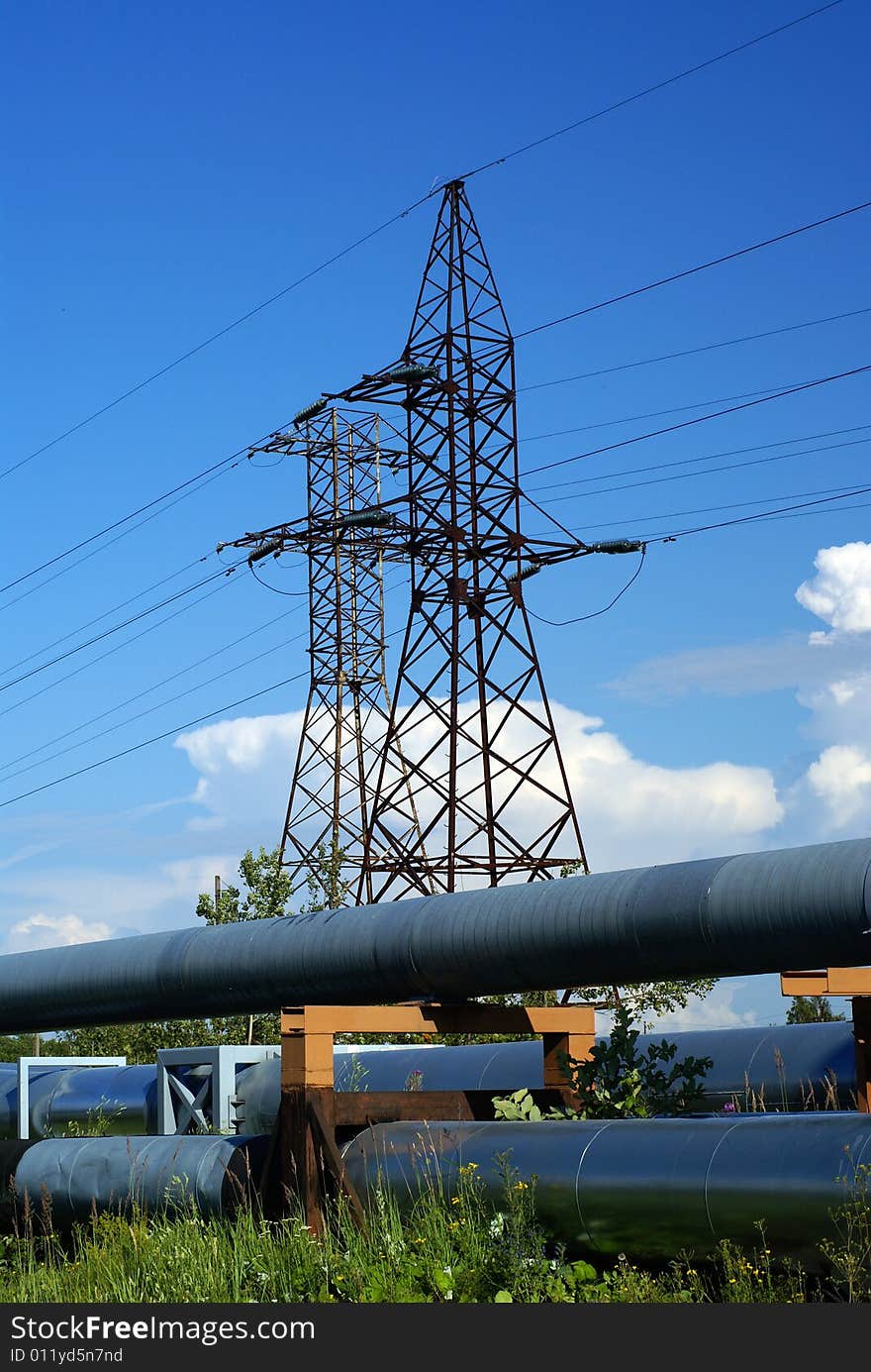 Industrial pipelines on pipe-bridge and electric power lines  against blue sky. Industrial pipelines on pipe-bridge and electric power lines  against blue sky