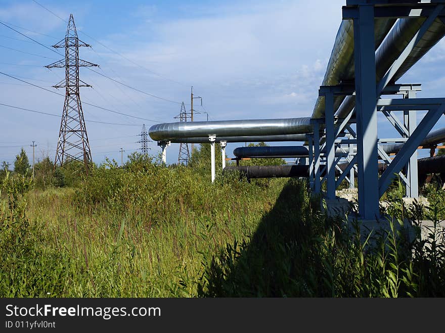 Industrial pipelines on pipe-bridge and electric power lines  against blue sky. Industrial pipelines on pipe-bridge and electric power lines  against blue sky