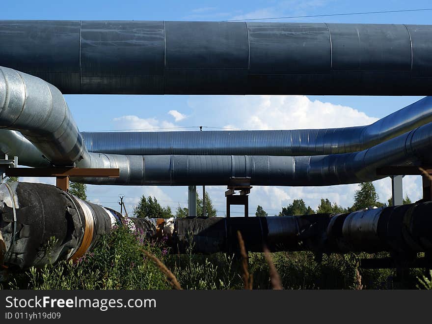 Industrial pipelines on pipe-bridge and electric power lines  against blue sky. Industrial pipelines on pipe-bridge and electric power lines  against blue sky