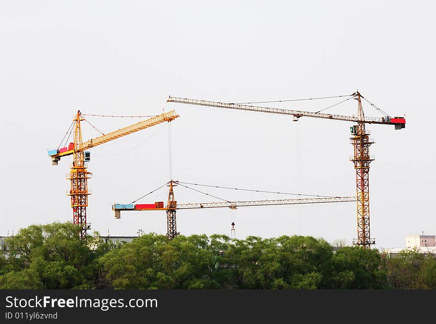 Three high cranes at building site.