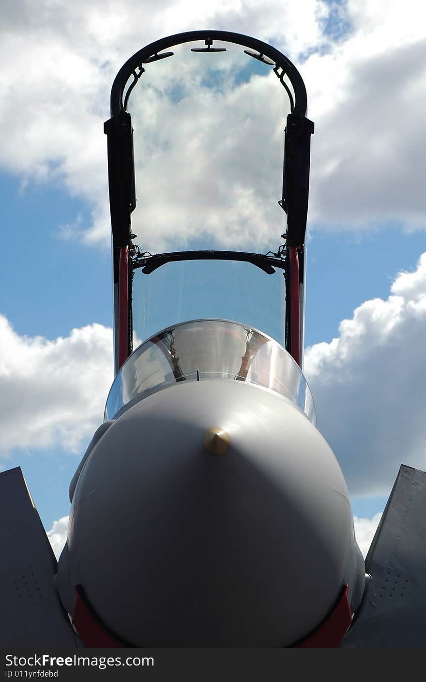 Jet fighter canopy silhouette against a blue cloudy sky