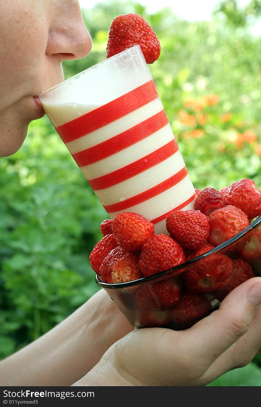 Red strawberry and glass milk in the hands