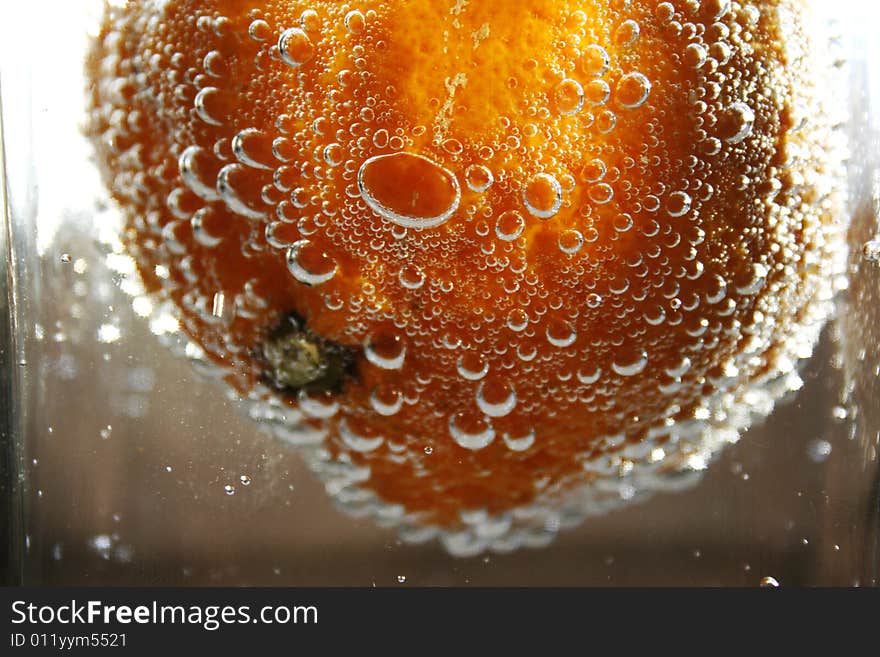 Tangerine in water with bubbles in a glass vase. Tangerine in water with bubbles in a glass vase